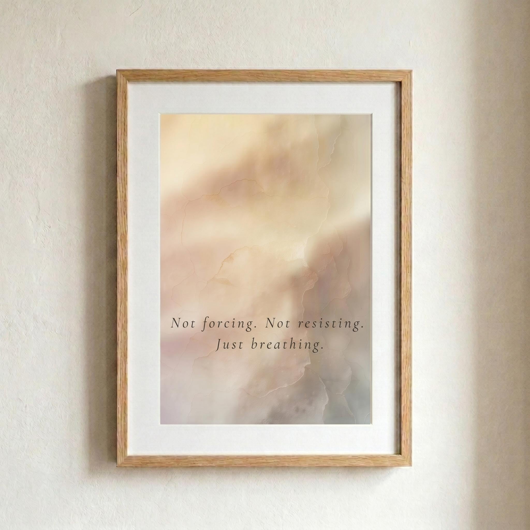A framed art print with a light wood frame and white mat, featuring an abstract soft-focus background in warm beige and pink tones with the text 'Not forcing. Not resisting.